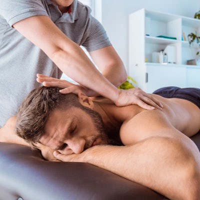 Massage therapist massaging back of the young man